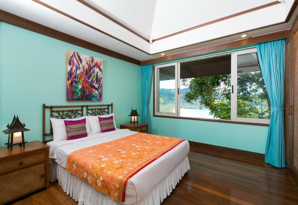 a bedroom with a bed with blue walls and a window at Katamanda villa Sooksan in Kata Beach