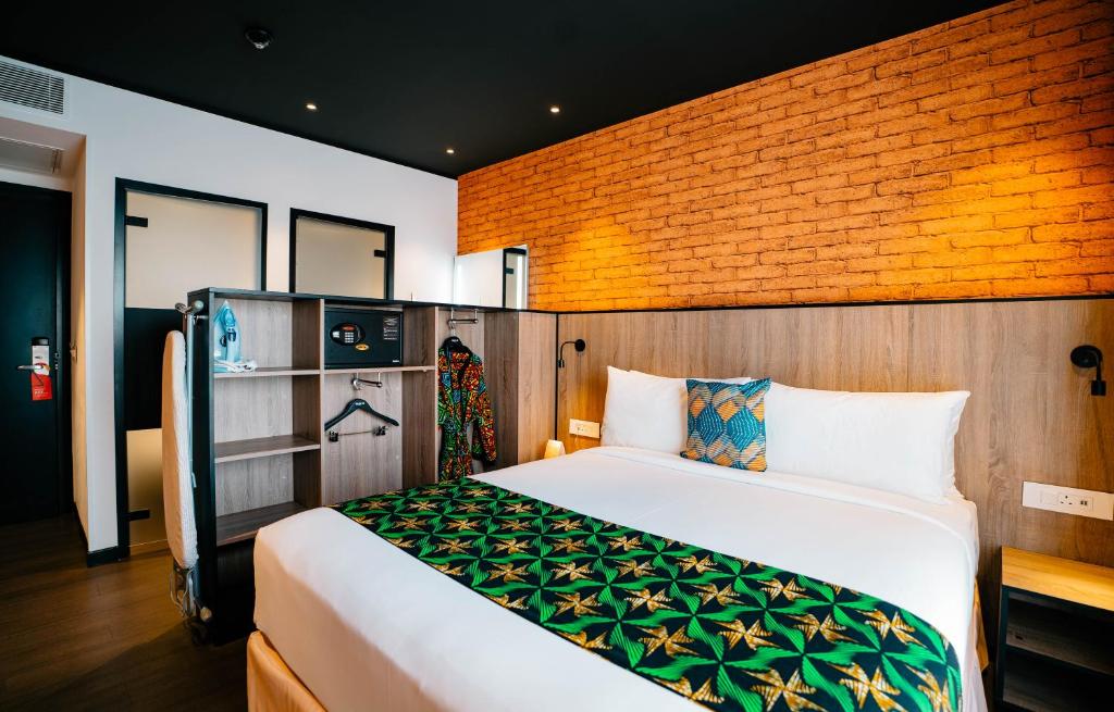 a bedroom with a bed and a brick wall at ONOMO Hotel Kampala in Kampala