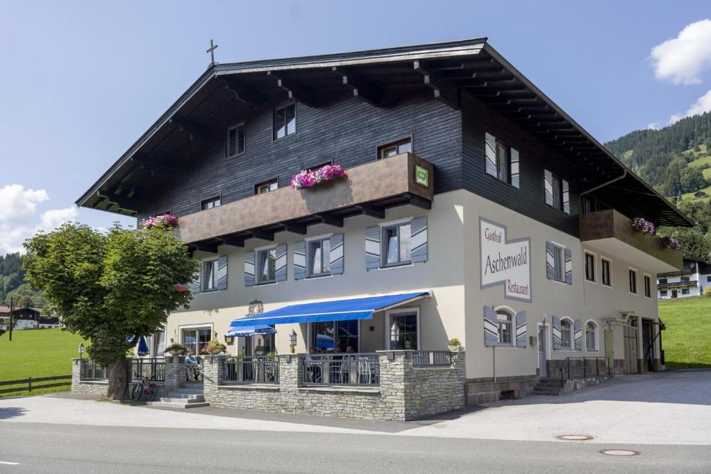 a large black and white building with a tree at Gasthof Aschenwald in Westendorf