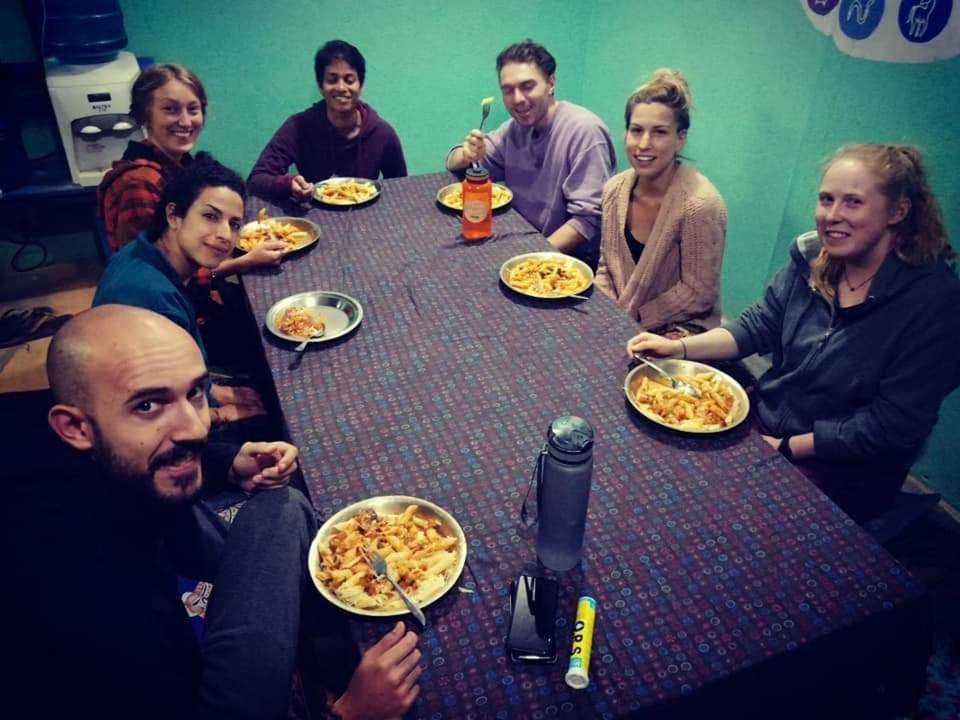 un grupo de personas sentadas alrededor de una mesa comiendo pizza en Sunrise Farmstay en Katmandú