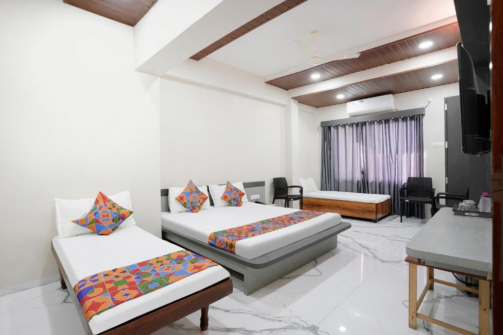 a hotel room with two beds and a television at FabHotel Priya Lodging, near Ojhar Airport in Nashik