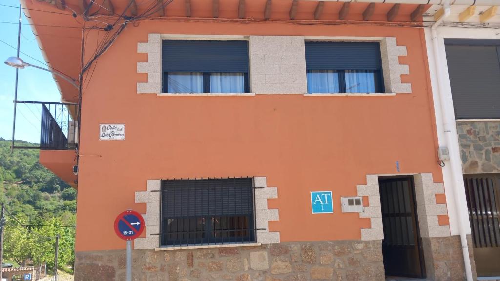 ein orangefarbenes Gebäude mit zwei Fenstern und einem Tor in der Unterkunft Apartamento Turístico Dalmacia in Gata