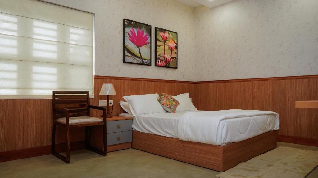 a bedroom with a bed and a chair and a window at Waterlily Homestay in Kottayam