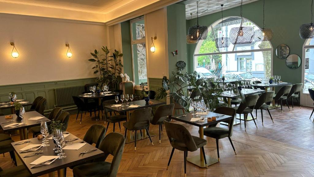 um restaurante com mesas e cadeiras num quarto em Logis Hôtel Restaurant Grand Hôtel de Lyon em Vals-les-Bains