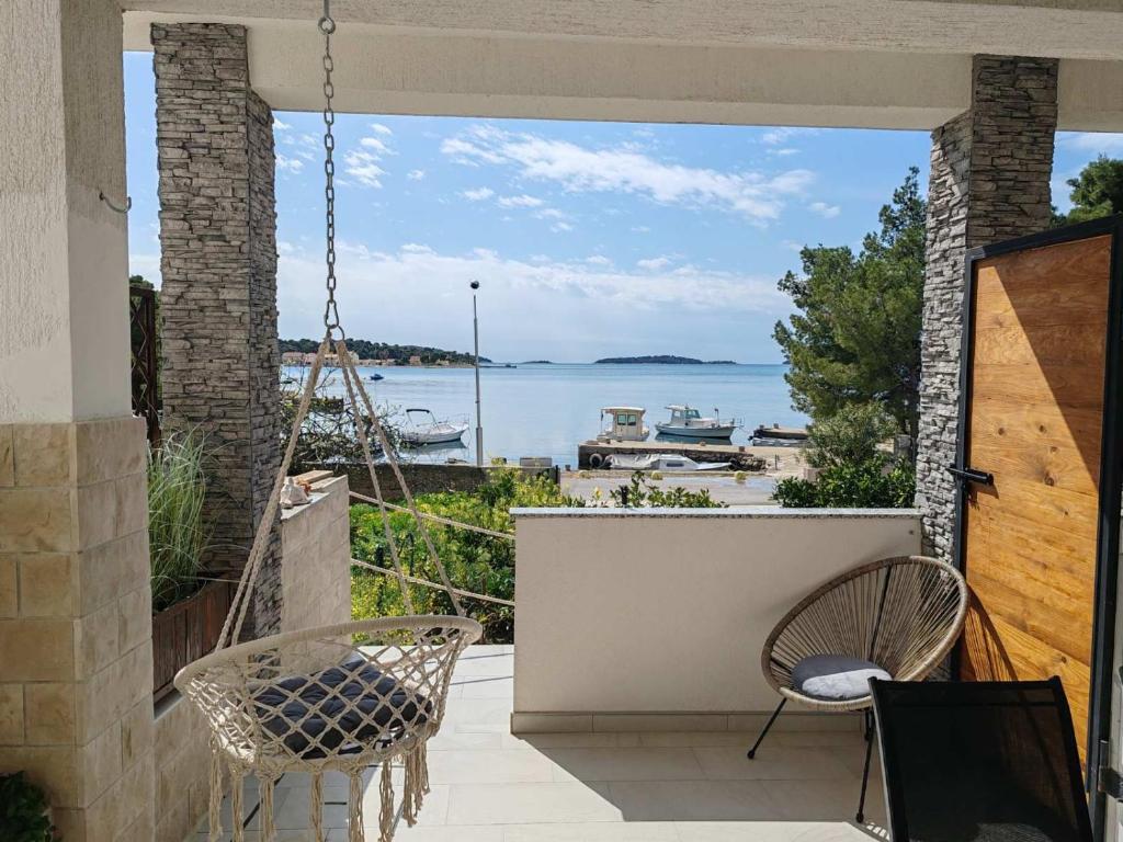 Un porche con dos sillas y vista al agua. en Apartments Alisa, en Brodarica