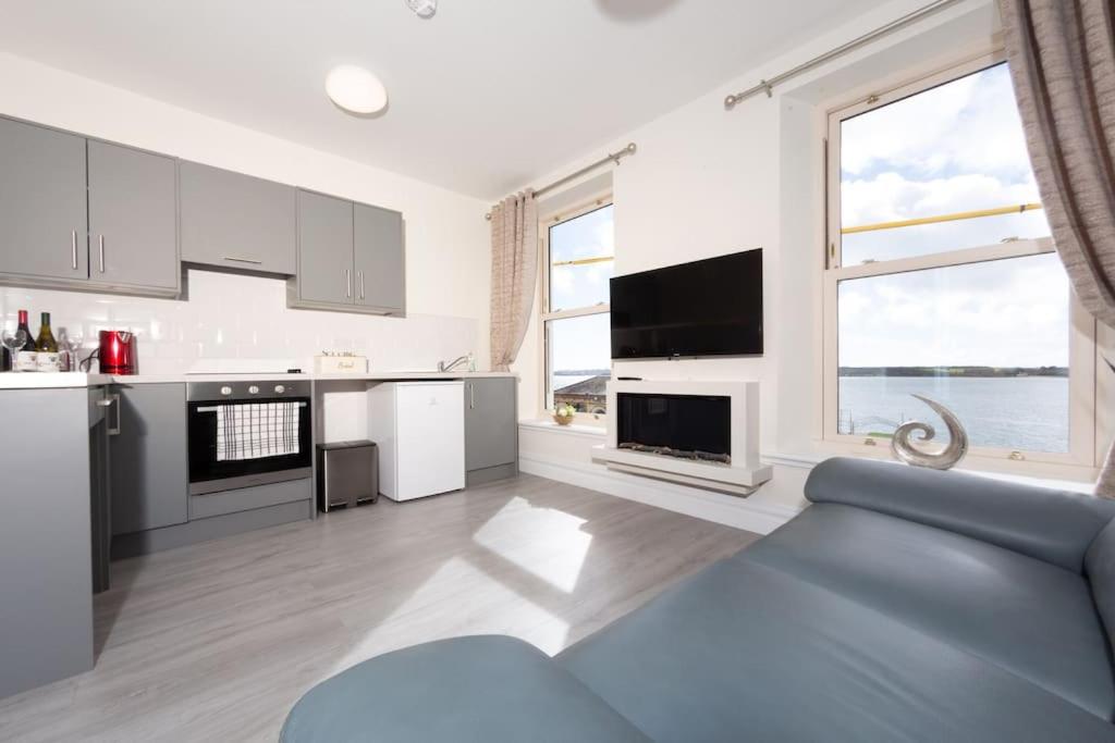 a kitchen with white cabinets and a blue couch at Unit 2 Island View Apartments With Stunning Harbour View in Cobh