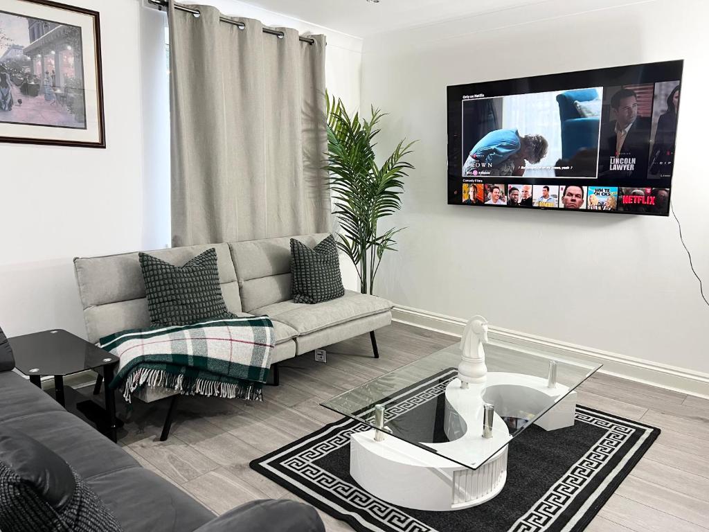 a living room with a couch and a tv on the wall at Majestic 2 bedroom House Milton Keynes in Milton Keynes