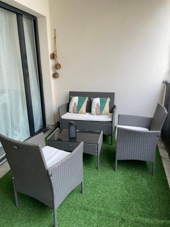 een patio met stoelen en een bank met kussens bij Sweet Escape Paris Centre - 3 bds- terrasse - Stade de France - Montmartre in Saint-Ouen