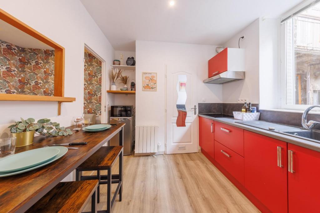 une cuisine avec des placards rouges et une table en bois dans l'établissement Le Bercail - Joli studio proche commodités, à Clermont-Ferrand