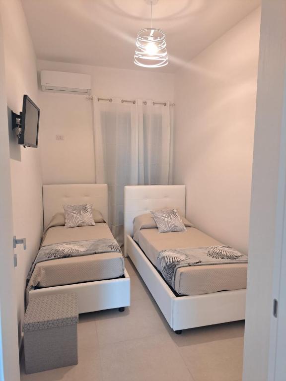 2 łóżka w pokoju z białymi ścianami w obiekcie Costamia Casa Vacanze w mieście Santa Maria di Castellabate