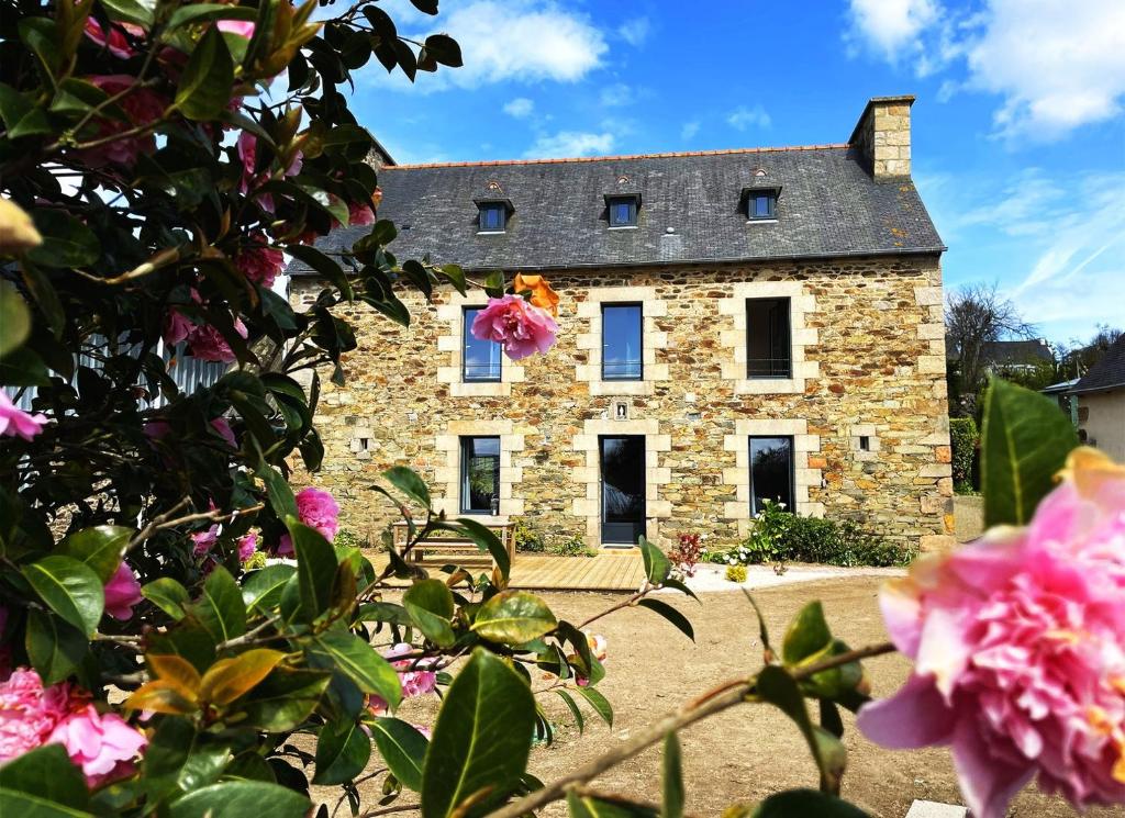 uma velha casa de pedra com flores em frente em La Ferme de Kersa em Ploubazlanec