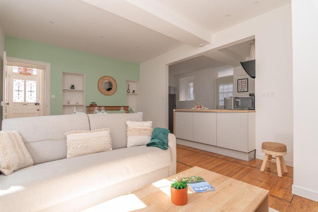 een woonkamer met een witte bank en een keuken bij Magnifique logement spacieux hyper centre in Nuits-Saint-Georges