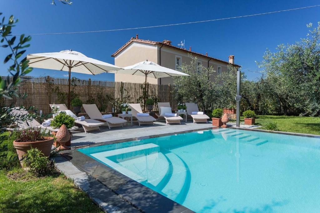 a swimming pool with chairs and umbrellas at Villa Principessa Elisa, Amazing Views, Spa & Private Pool in Capannori