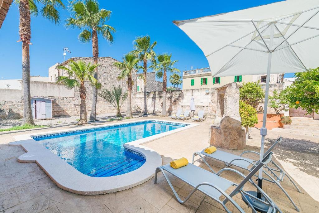 a swimming pool with a white umbrella and chairs and a table and an umbrella at Villa Sa Verdera in Maria de la Salut