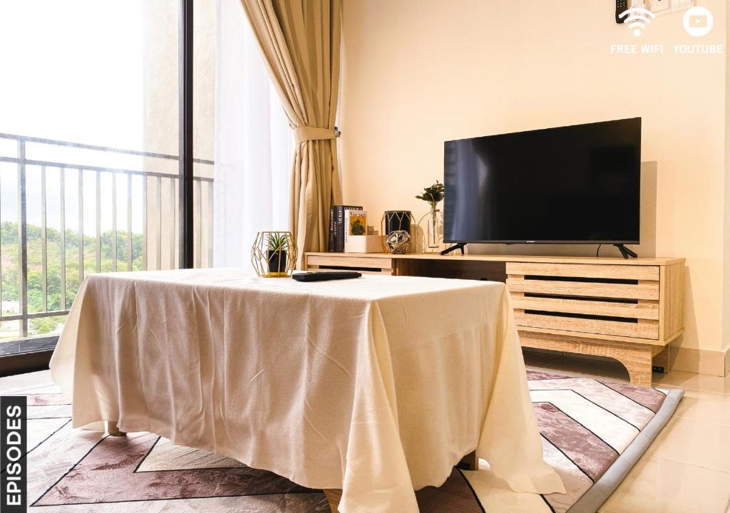 ein Wohnzimmer mit einem Tisch und einem TV in der Unterkunft Cozy 2 Rooms Nilai Free Wifi 03 in Nilai
