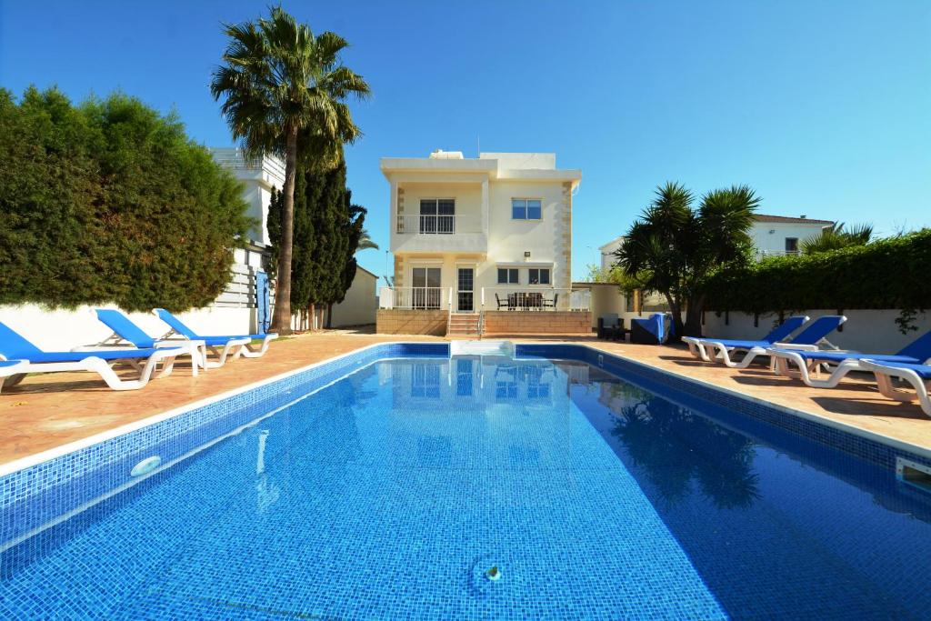 a swimming pool with chairs and a house at Villa Chloe in Ayia Napa