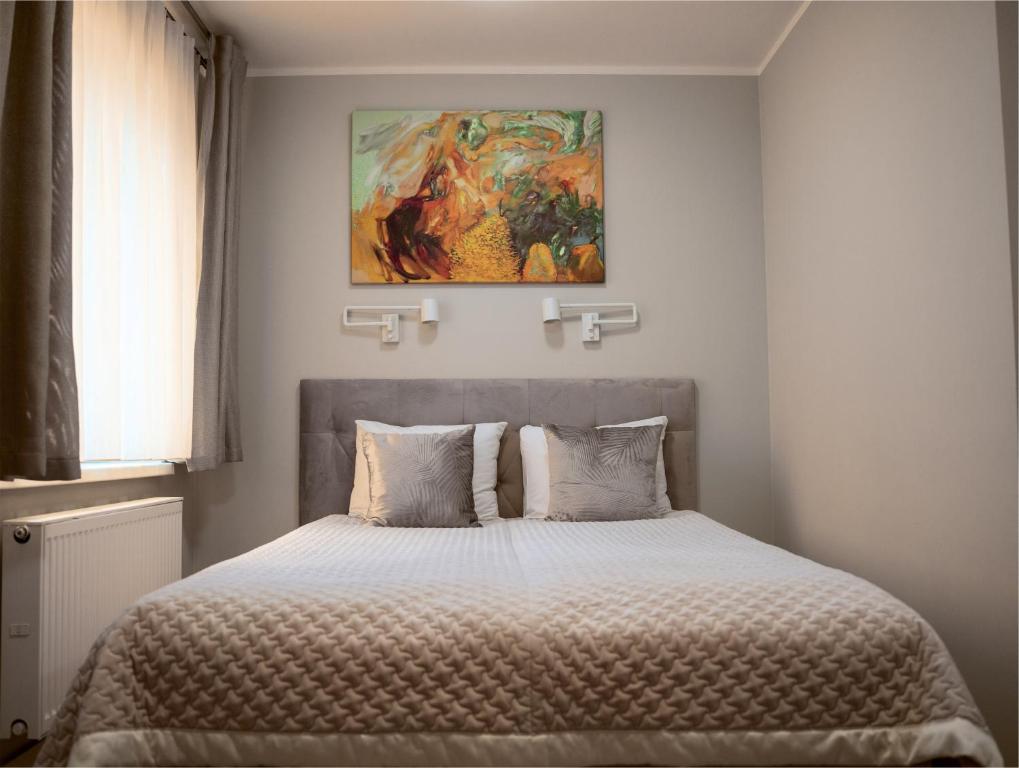 a bedroom with a bed with a painting above it at Apartamenty Pyskowice in Pyskowice