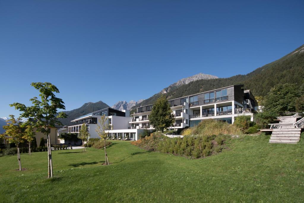 un gran edificio en una colina con un campo verde en Hotel & Appartements Oberhofer, en Telfes im Stubai