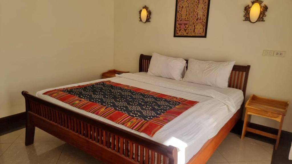 a bed with a blanket on it in a room at Phasouk Viengmai Villa in Luang Prabang