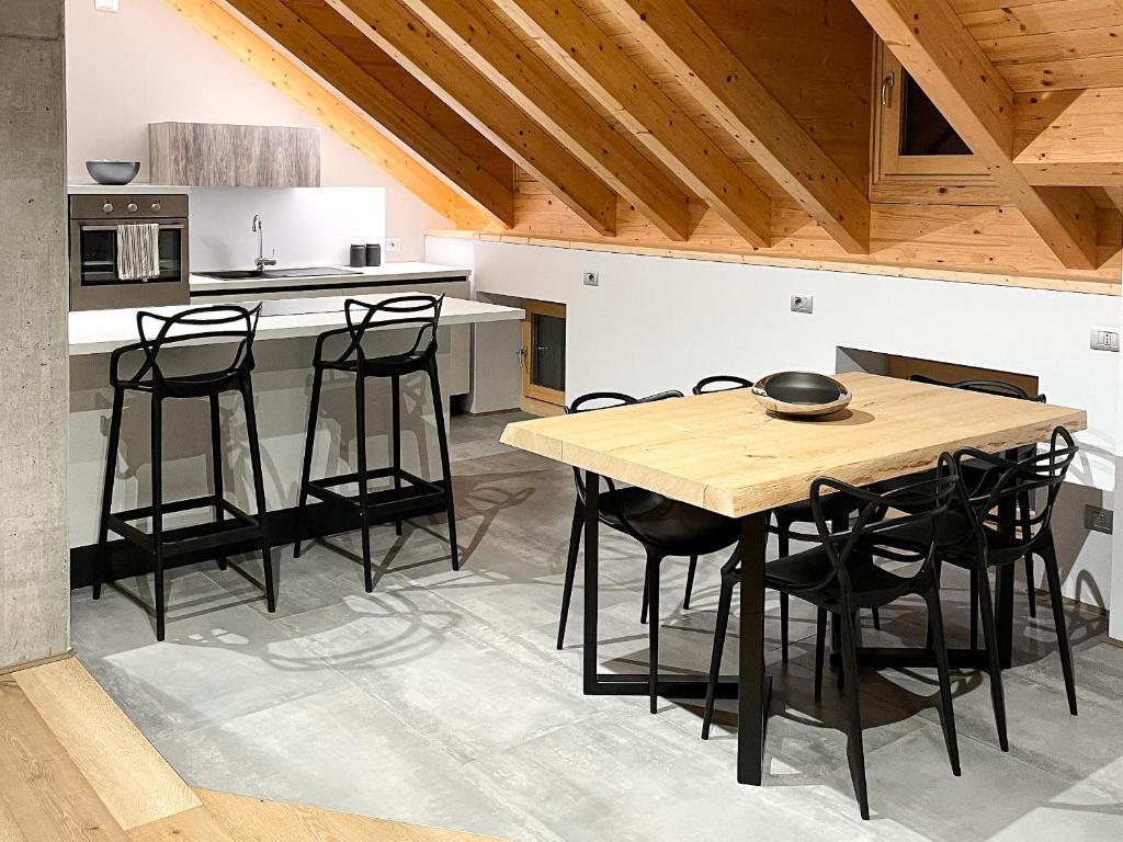 uma cozinha com uma mesa de madeira e cadeiras pretas em Appartamento Moderno ed Esclusivo - Casa Pierina em Lastebasse