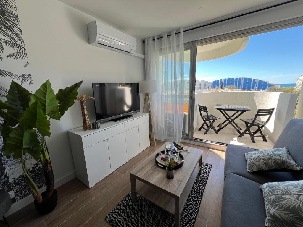 un salon avec un canapé et une télévision dans l'établissement Superbe Studio Cabine Vue Mer 3 étoiles *, à La Grande Motte