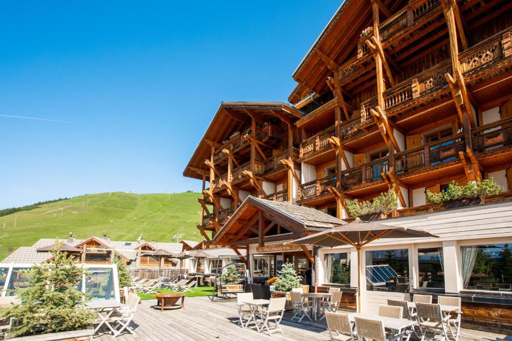 un gran edificio de madera con sillas y mesas en Hôtel Au Chamois d'Or by Les Etincelles, en L'Alpe-d'Huez