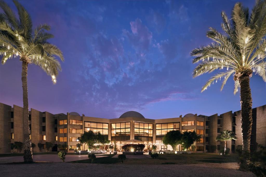 a building with palm trees in front of it at InterContinental Al Jubail Resort in Al Jubail