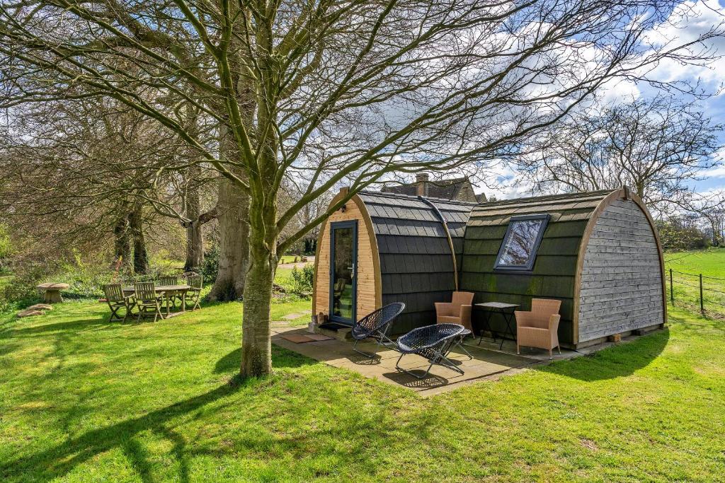 a green tiny house in a field with a tree at Finest Retreats - The Pods in Camerton