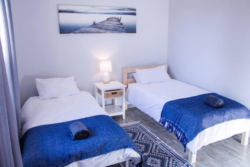 1 Schlafzimmer mit 2 Betten, blauen Decken und einem Tisch in der Unterkunft Neat & New Private 2 bedroom Backyard Flat. in Windhoek
