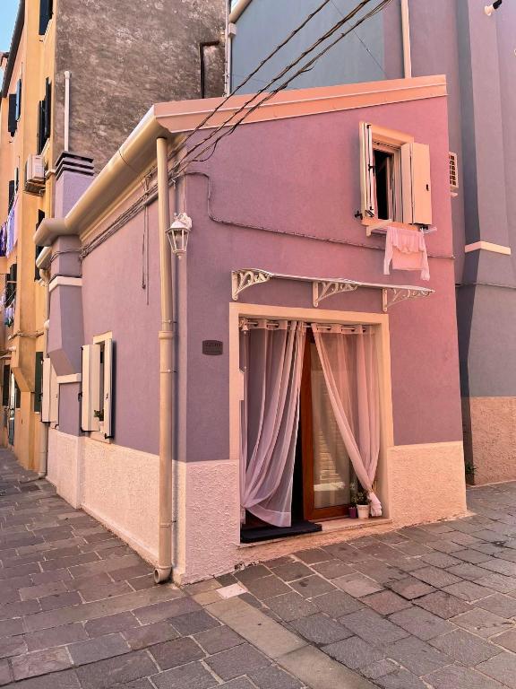 a pink building with a window with a curtain at La dolce dimora in Chioggia
