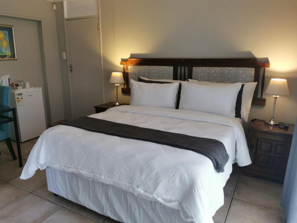 een slaapkamer met een groot bed met witte lakens en kussens bij 19th on Bloekom Guesthouse in Secunda