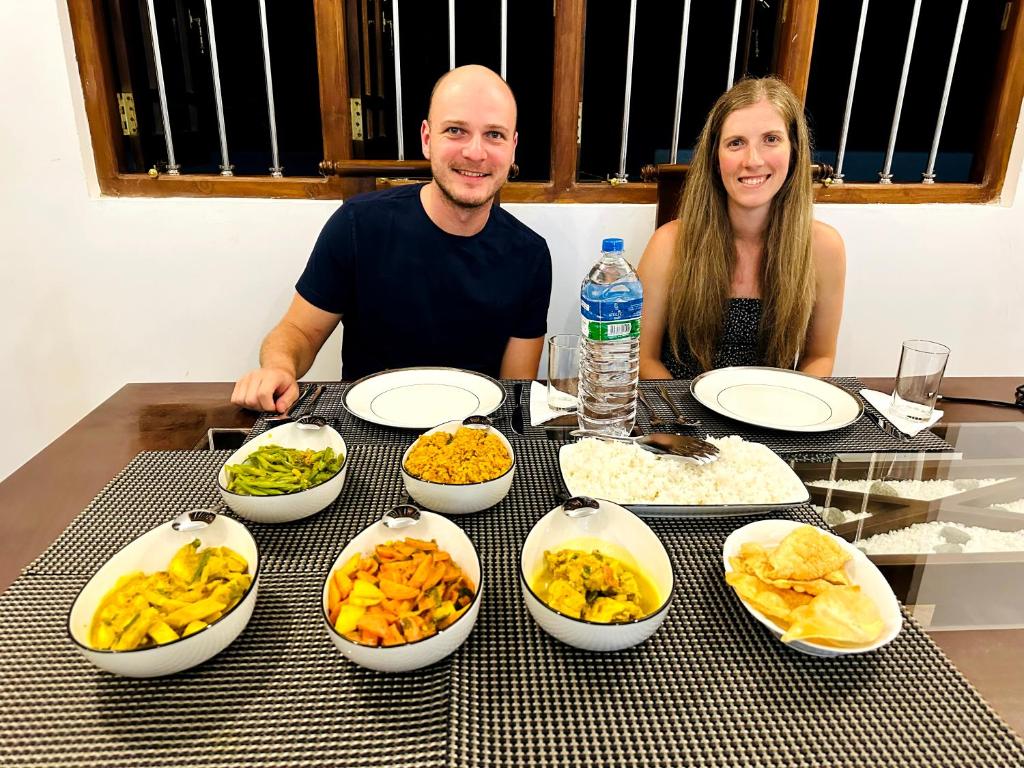 a man and woman sitting at a table with bowls of food at Residence Inn in Udawalawe