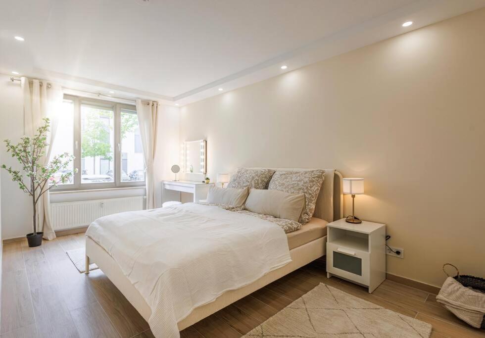 ein weißes Schlafzimmer mit einem Bett und einem Fenster in der Unterkunft Schöne Wohnung mit Terrasse Nähe Airport in Schönefeld
