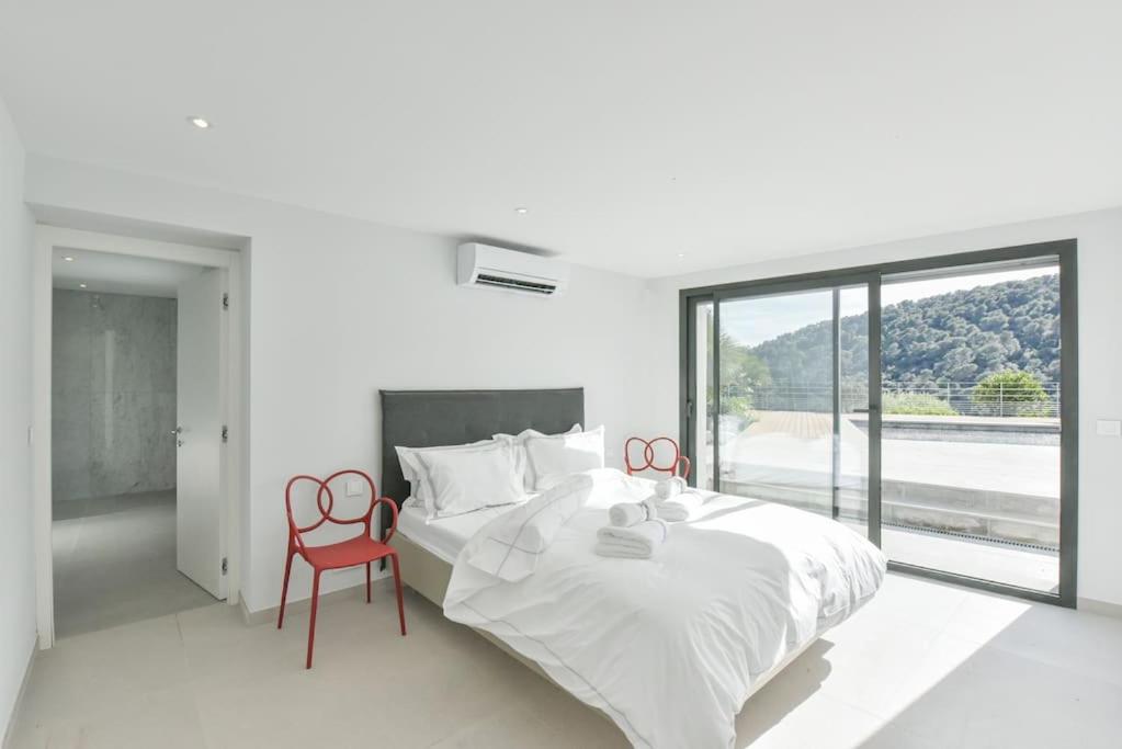 een witte slaapkamer met een groot bed en een rode stoel bij VILLA ARTSY - Fully renovated villa with pool, AC, wi-fi - 8 ppl in Vence