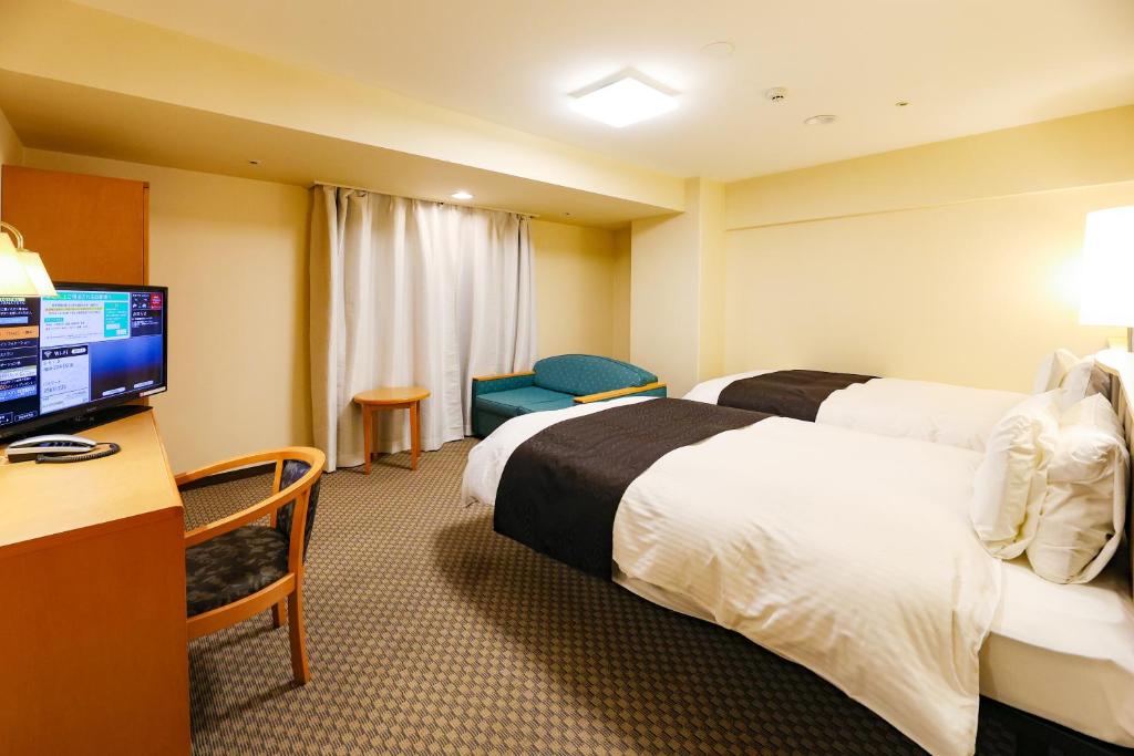 a hotel room with two beds and a flat screen tv at APA Hotel Obihiro Ekimae in Obihiro