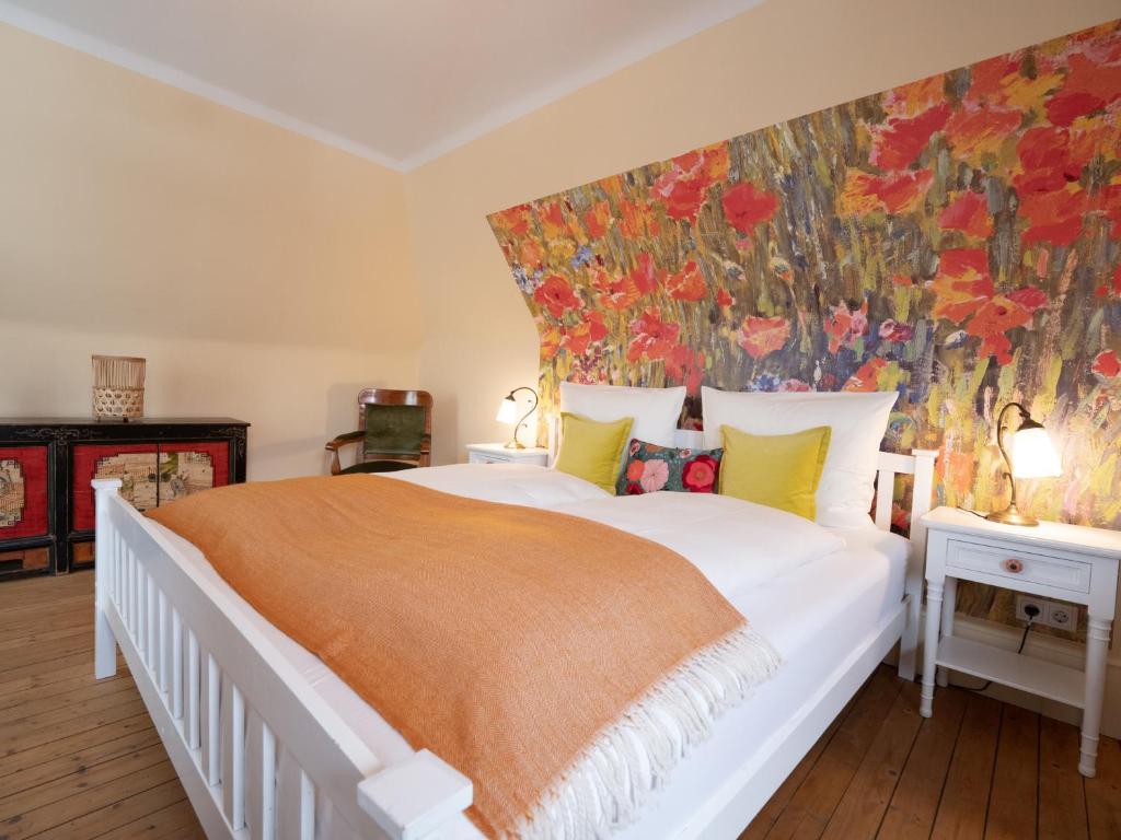 a bedroom with a large white bed with an orange blanket at REFUGIUM Theresienstraße 19 - Chambre Vonnoh in Rhodt unter Rietburg