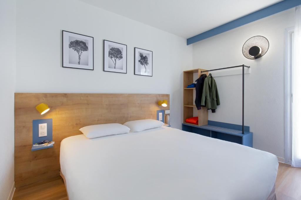 a bedroom with a white bed and some pictures on the wall at ibis Styles Aubagne Gemenos in Gémenos