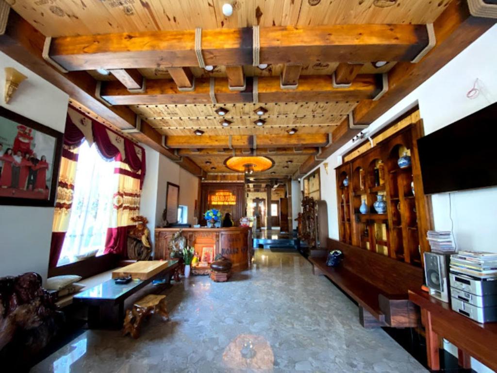 Hoàng Khiêm Hotel في بلاي كو: غرفة معيشة كبيرة مع سقف خشبي