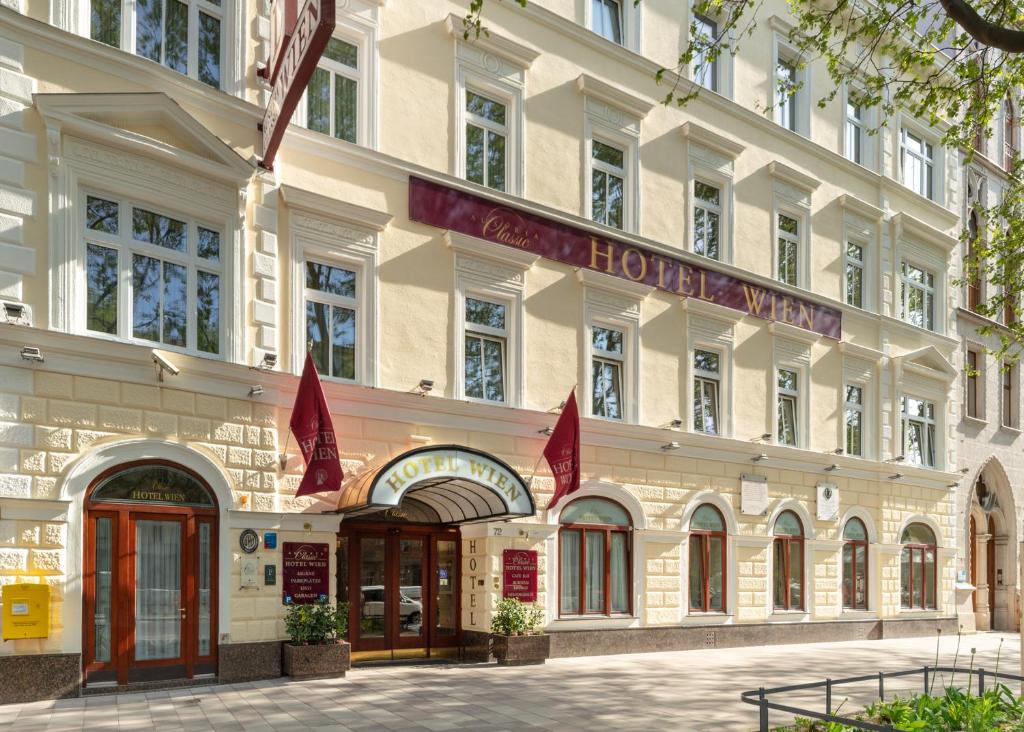 un gran edificio con banderas rojas delante de él en Austria Classic Hotel Wien, en Viena