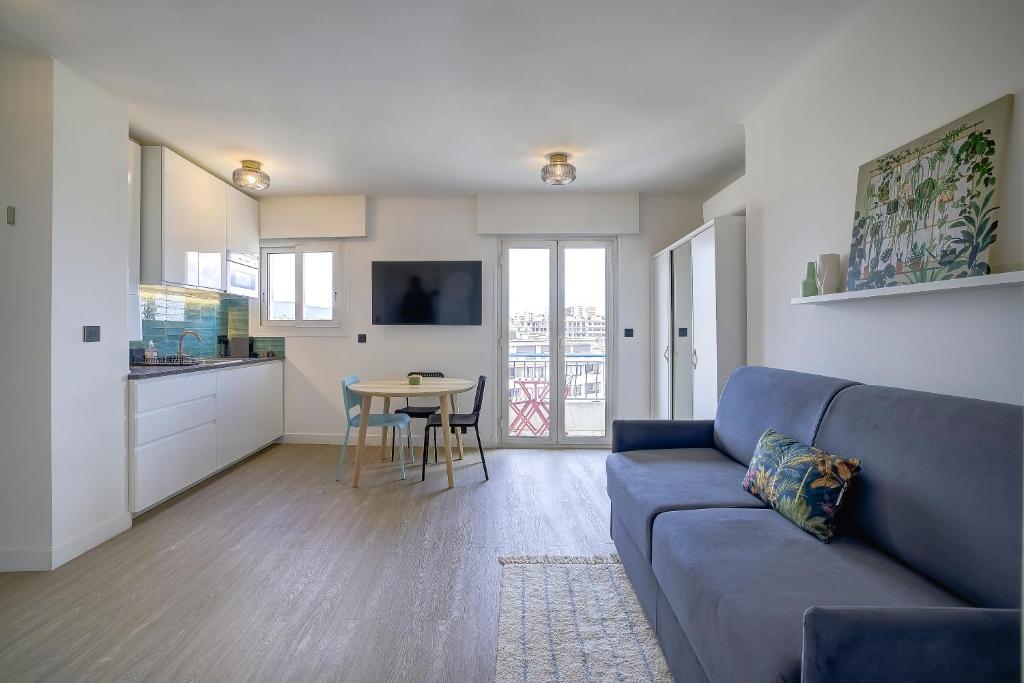 un salon avec un canapé bleu et une table dans l'établissement Magnifique studio Le Dauphin 50m des plages, à Juan-les-Pins