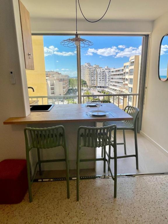 une cuisine avec une table et des chaises ainsi qu'une grande fenêtre dans l'établissement Carnon - Magnifique T2 - Plage à 2 min à pied, à Mauguio