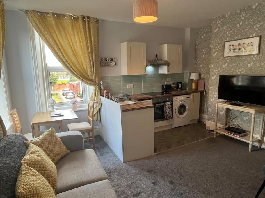 a kitchen and living room with a couch and a table at Apartment 3 Petteril House in Carlisle