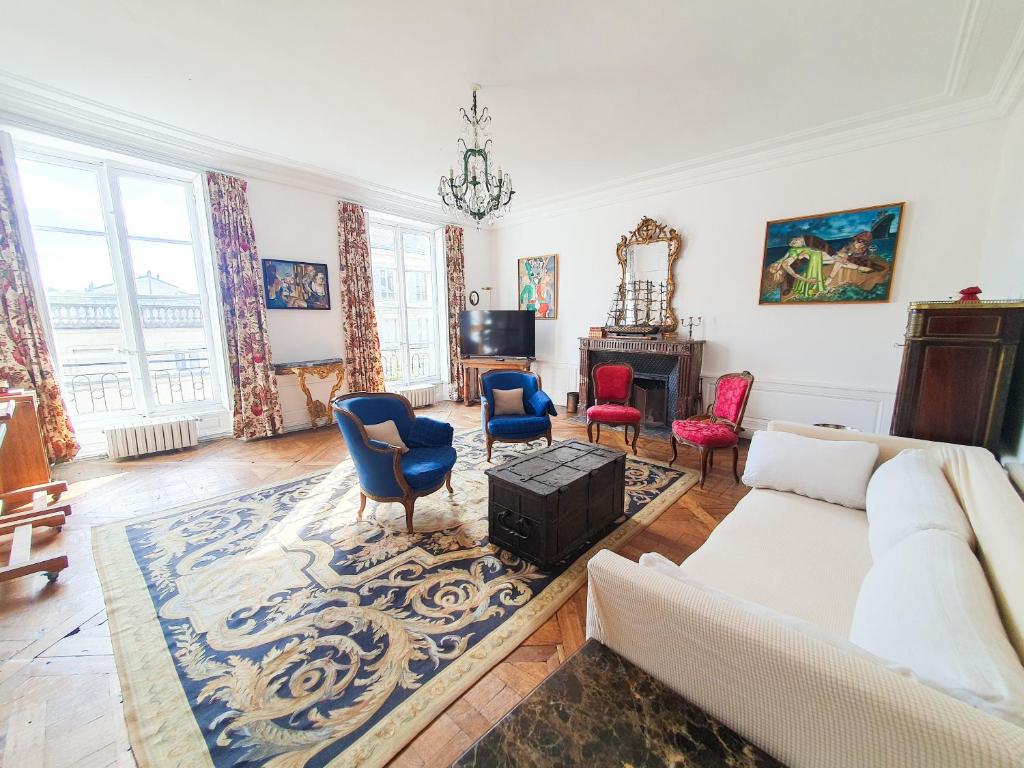 uma sala de estar com um sofá branco e cadeiras em Magnifique appartement au coeur de Versailles em Versailles