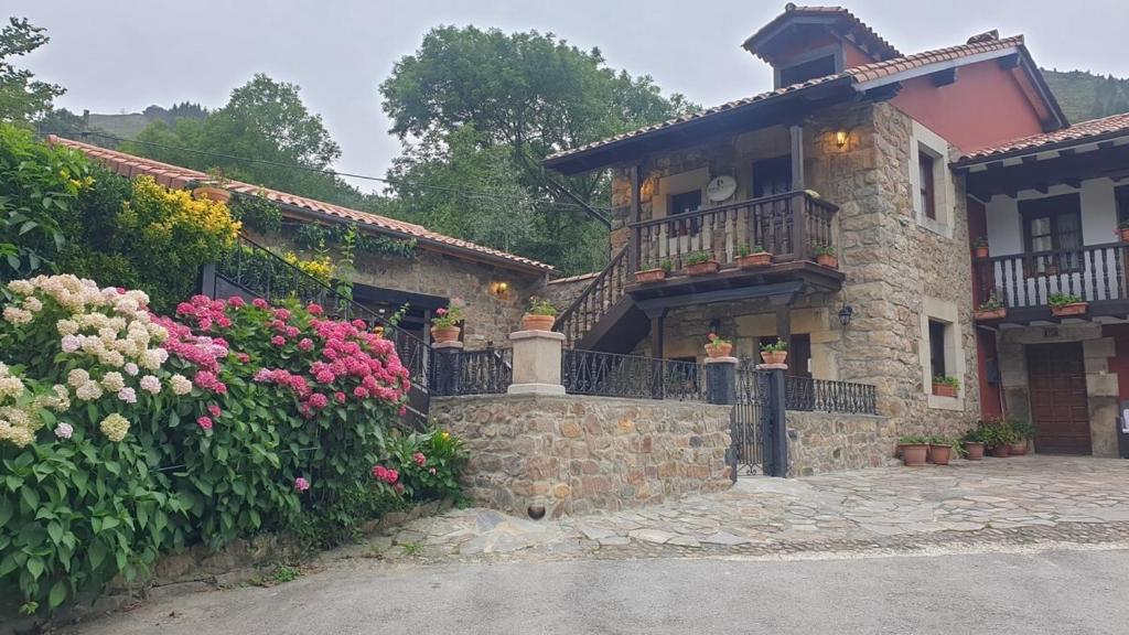 a stone house with flowers in front of it at casa rural CABORZAL in Renedo