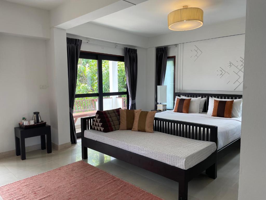 sypialnia z łóżkiem, kanapą i oknem w obiekcie Yindee Stylish Guesthouse w mieście Chiang Mai