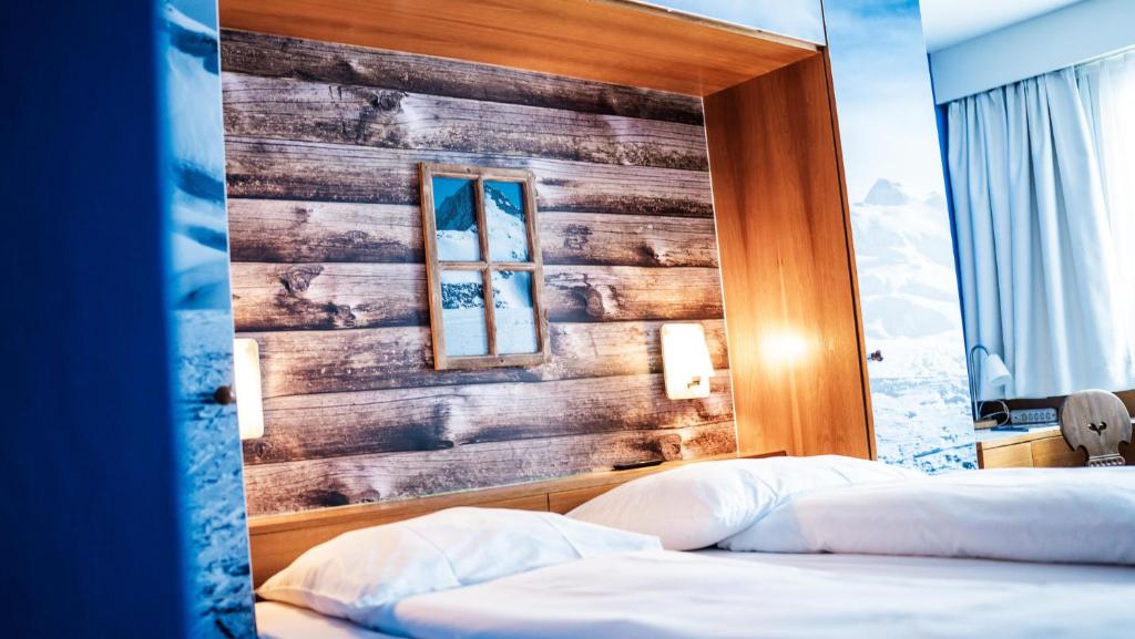 a bedroom with two beds and a wooden wall at Boutique Hotel Kronenhof in Zurich