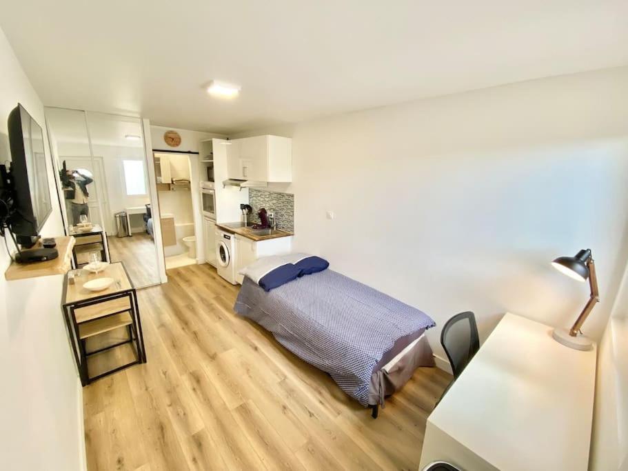 Kleines Zimmer mit einem Bett und einer Küche in der Unterkunft Cosy Studio neuf centre-ville in Orsay