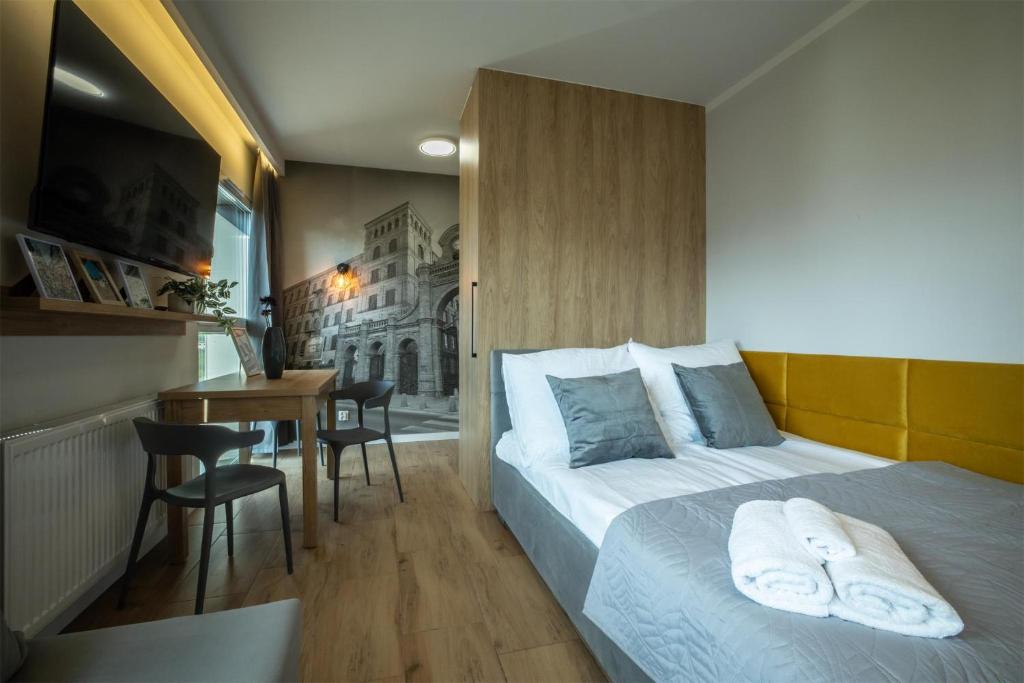 a bedroom with a bed and a table with chairs at WiguryTower Apartaments 98 in Łódź