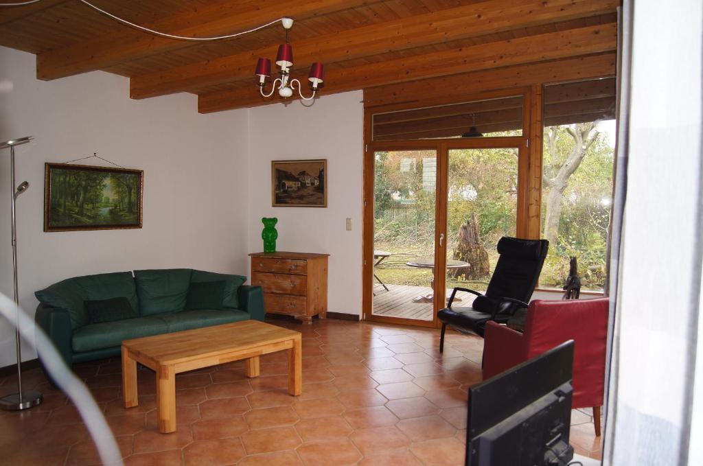ein Wohnzimmer mit einem grünen Sofa und einem Tisch in der Unterkunft Mitten im Garten in Friedland