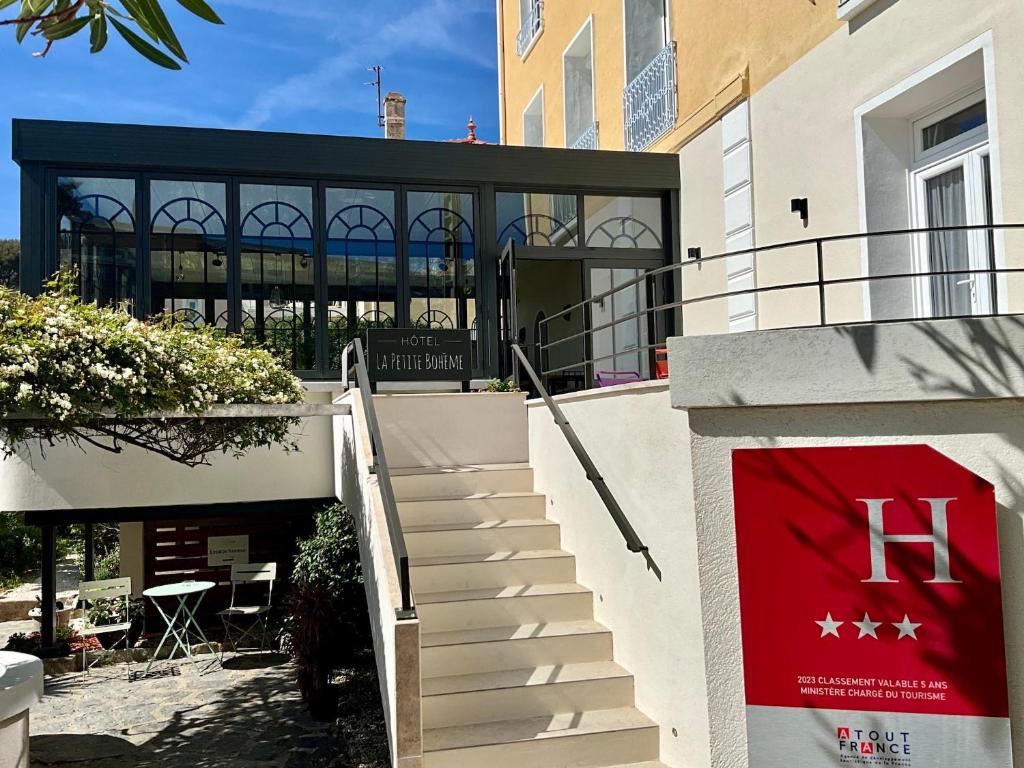 un escalier menant à un bâtiment avec drapeau rouge dans l'établissement Hôtel La Petite Bohème, au Lavandou